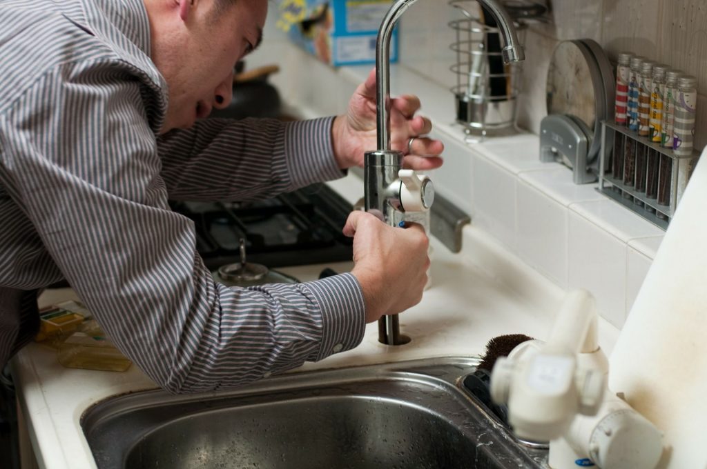 A man fixing a kitchen faucet