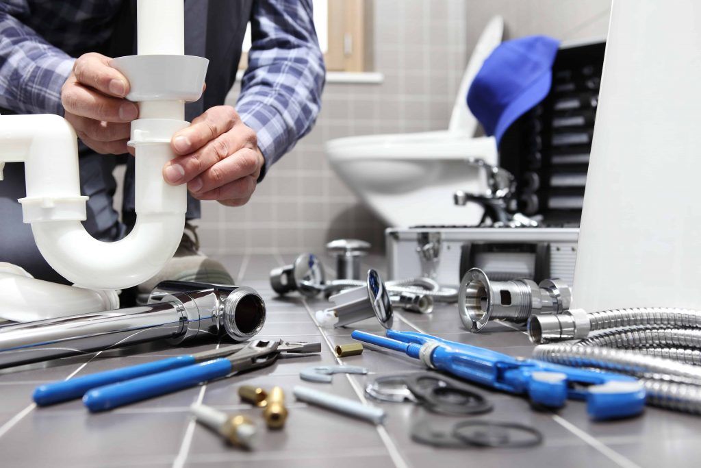 plumber fixing pipe, toilet in background