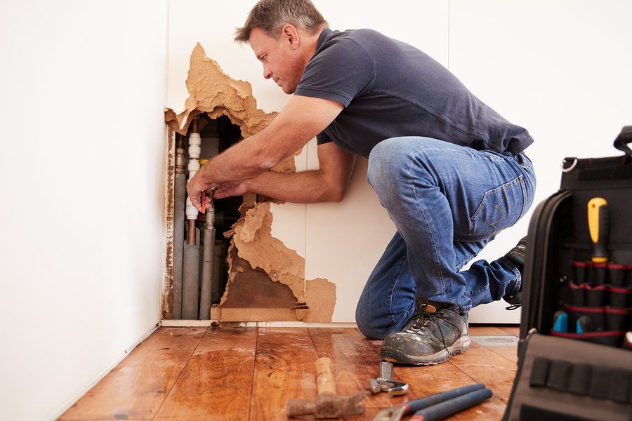 Man fixing pipes behind wall