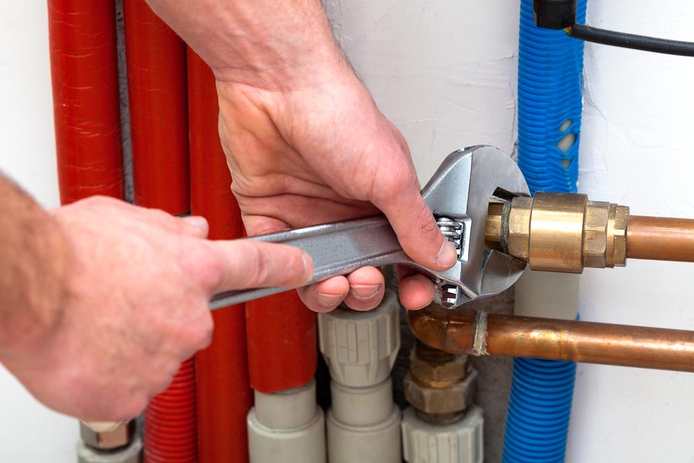 Man's hands with wrench turning off valves